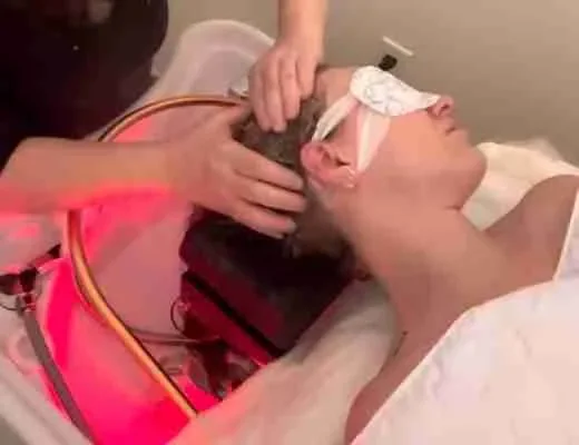 Soin capillaire avec lumière rouge sur une cliente allongée.